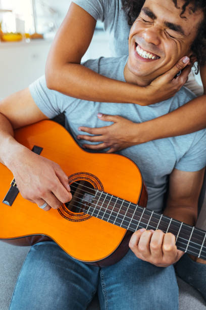 istock Young couple smiling happy playing classical guitar sitting on the sofa at home 1387263814
