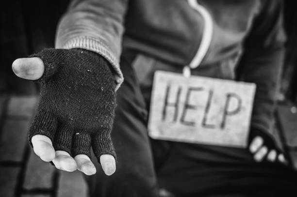 бездомный сидит на улице, умоляя о помощи - panhandling стоковые фото и изображения