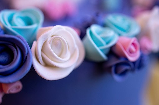 Close-up on multi colored sugar icing roses for cake decoration on cake upper rim at confectioner's