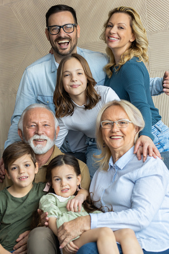 Seven member family is smiling and posing to a photographer while having family portrait session.