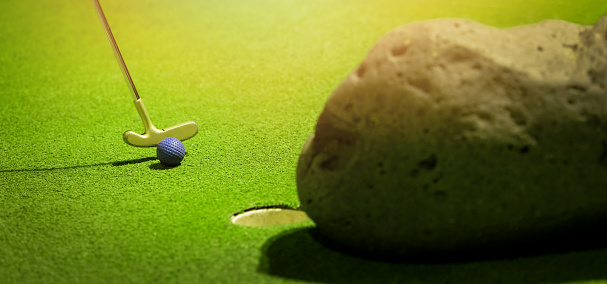 mini golf  - putter hit the ball on green artificial grass. banner with copy space