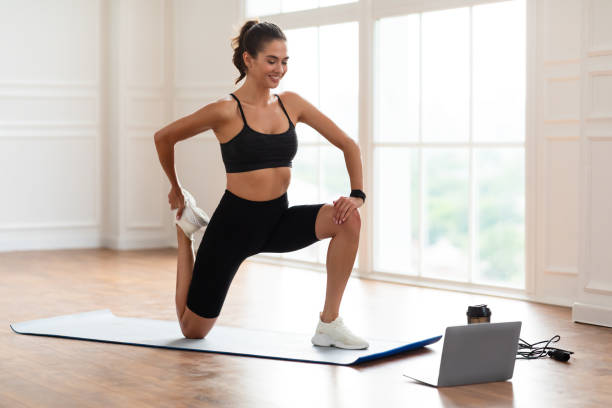 istock Cheerful woman stretching leg muscles using pc 1387266920