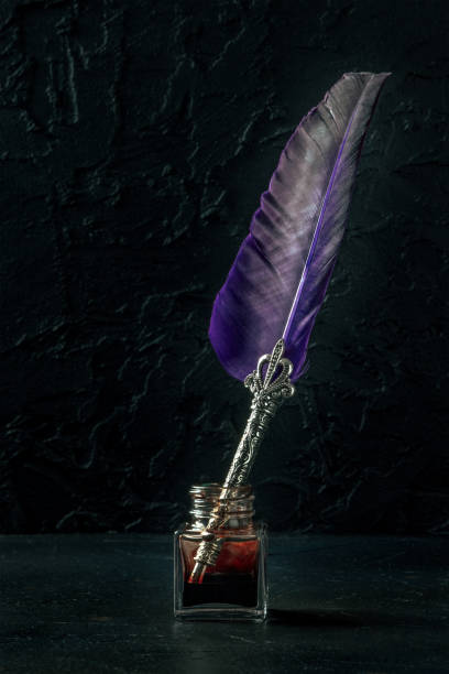 istock Feather quill pen with a vintage ink well, a side view on a black background 1387267053