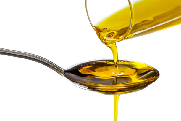 Extra virgin oil poured into spoon Extra virgin oil poured from bottle into spoon, isolated on white background, clipping path olive oil pouring antioxidant liquid stock pictures, royalty-free photos & images