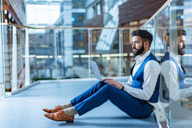 istock Business man sitting on the floor working on laptop 1387267912