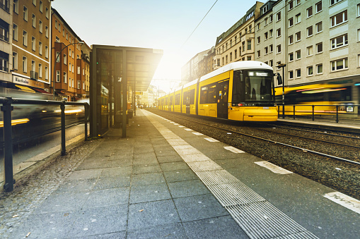 yellow street car approaching tram station at Rosenthaler Platz in Berlin Mitte in the backlit of sunrise