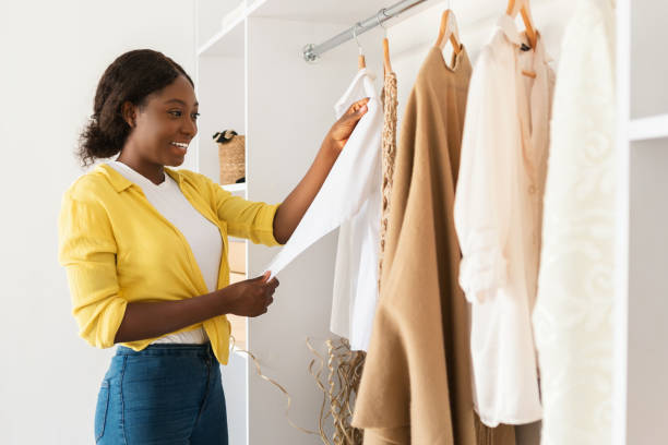 African American Woman Choosing Clothes In Wardrobe At Home African American Woman Choosing Clothes In Wardrobe Full Of Stylish Clothes And Outfits Standing At Home, Side View Shot. Shopping, Fashion And Style Concept. Commerce And Retail Wardrobe stock pictures, royalty-free photos & images