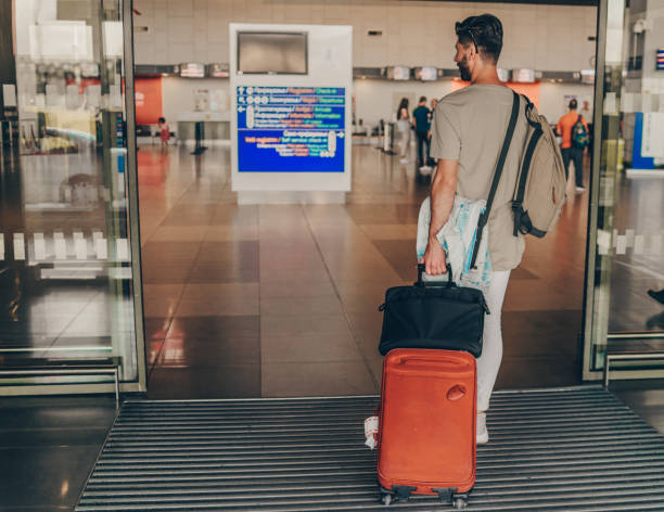 istock Positive adult guy is going to travel while pulling baggage 1387269812