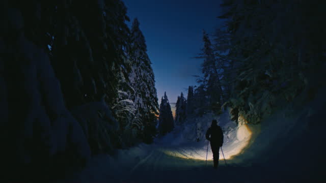 SLO MO Hiker walks in wintery forest at night