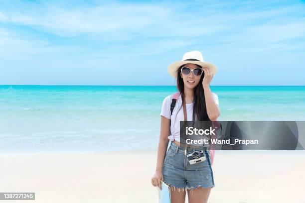 นักเดินทางที่มีความสุขและหญิงสาวการท่องเที่ยวเดินทางในช่วงฤดูร้อนบนชายหาด  คนเอเชียถือ ภาพสต็อก - ดาวน์โหลดรูปภาพตอนนี้