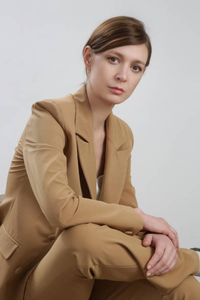 istock Female model wearing beige tailored suit and white silk top. Studio shot. 1387271673