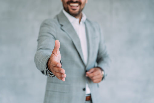 Shot of a businessman with an open hand ready for handshake. Focus is on the hand.