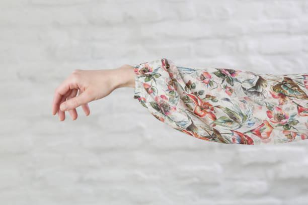 Woman's arm in floral silk blouse, indoor image aganst white wall Woman's arm in floral silk blouse, indoor image aganst white wall viscose stock pictures, royalty-free photos & images