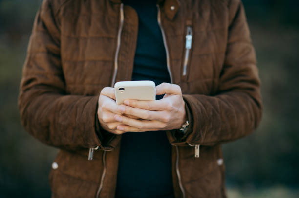 Young man holding smart phone reading text.
