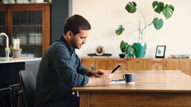 istock Shot of a young man using a digital tablet and going through paperwork at home 1387278544
