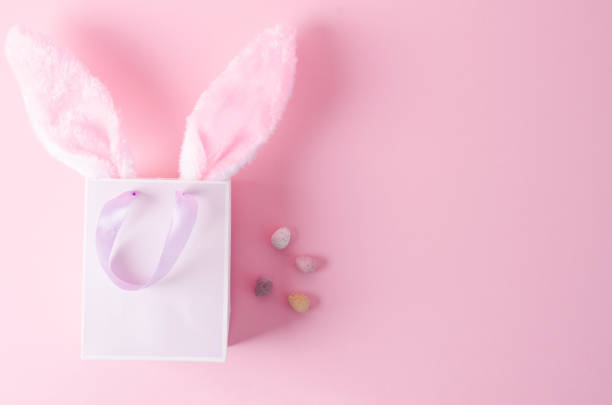 o conceito de comprar para a páscoa. saco de papel em um fundo rosa com orelhas de coelho em um fundo rosa, layout plano - rabbit ear antenna - fotografias e filmes do acervo