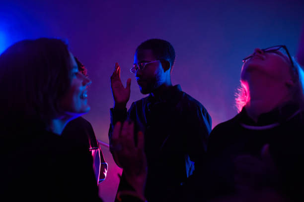 African American man Clubbing in Neon Light Back lit portrait of black young man dancing in crowd while partying in smoky club lit by neon, copy space public lighting stock pictures, royalty-free photos & images