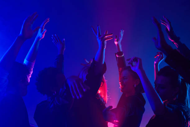 People Dancing in Neon Light Minimal shot of diverse crowd dancing in club with hands up lit by neon lights dance floor stock pictures, royalty-free photos & images