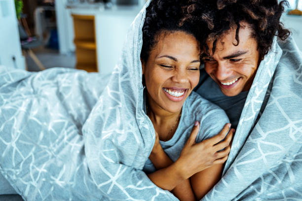 romantic couple embracing on sofa at home - winter women zen like photography imagens e fotografias de stock