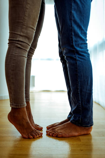 istock Low angle shot of a couple's feet while standing together at home 1387280710
