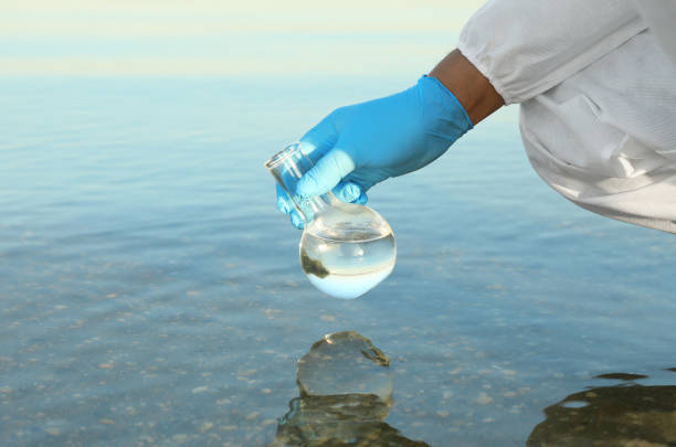 Tap water analysis quality control concept. Hand with a flask and water tap ckose up.