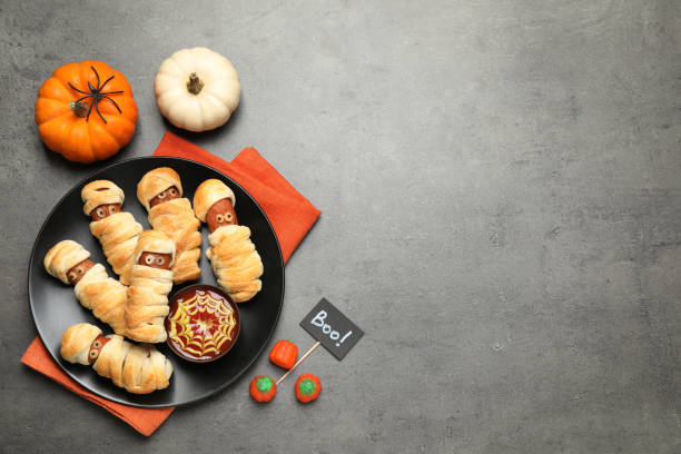 istock Spooky sausage mummies for Halloween party served on grey table, flat lay. Space for text 1387282611