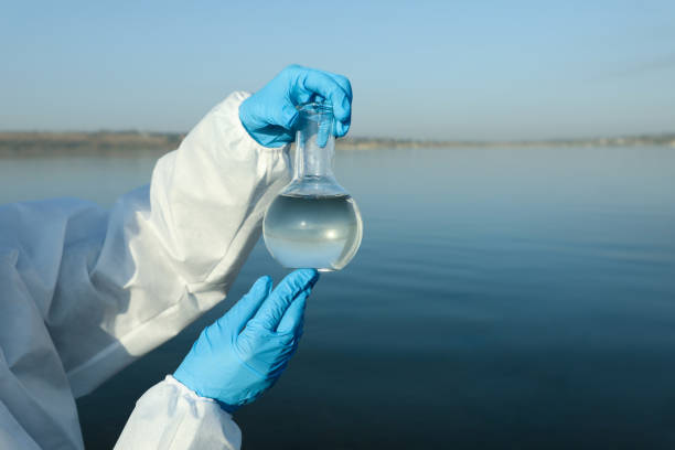 istock Scientist with florence flask taking sample from river for analysis, closeup 1387283774