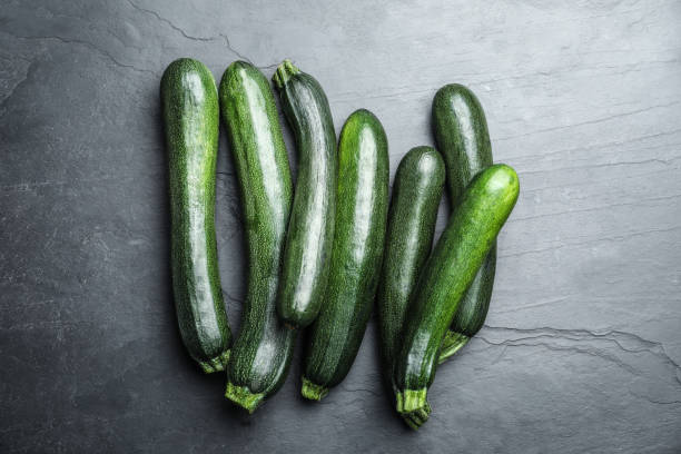 istock Green ripe zucchinis on black slate table, flat lay 1387283860