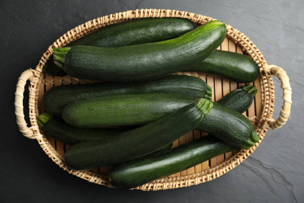 istock Basket with green zucchinis on black slate table, top view 1387285669