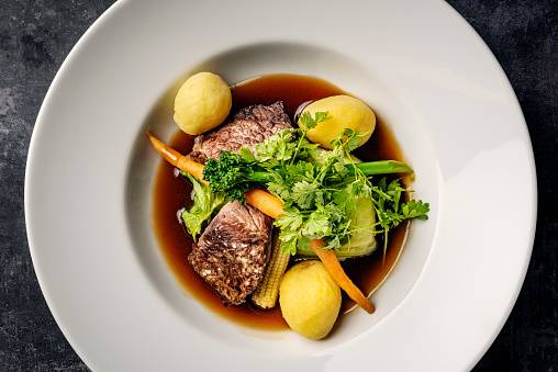 Overhead, close-up view of medallions of veal served with, bok choy cabbage, potatoes, carrots and broccoli with a madeira infused sauce. Colour, horizontal format with some copy space. Photographed on location in a restaurant on the island of Moen in Denmark.