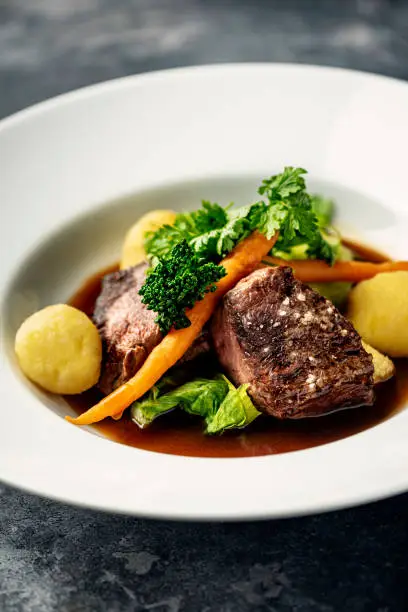 Overhead view of medallions of veal served with, bok choy cabbage, potatoes, carrots and broccoli with a madeira infused sauce. Colour, horizontal format with some copy space. Photographed on location in a restaurant on the island go Moen in Denmark.