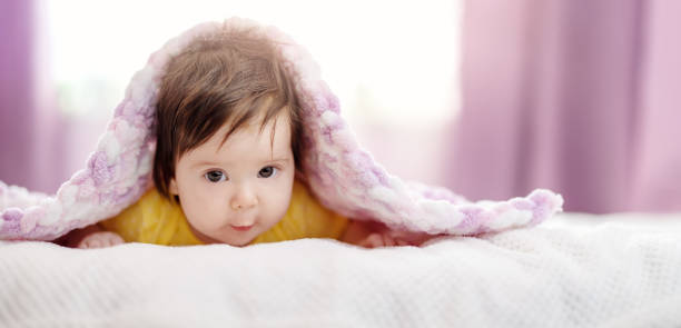 istock Cute little baby lying under pink blanket. 1387286160
