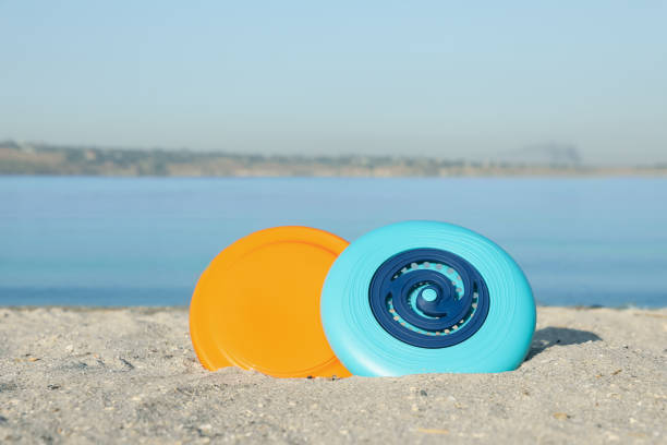 istock Plastic frisbee discs on sandy beach near river 1387286226