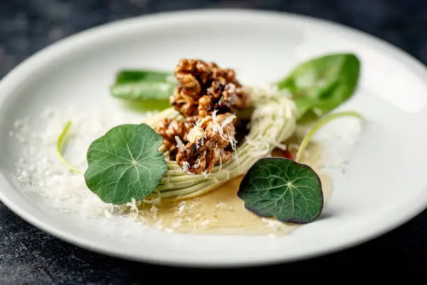 Blue cheese mousse with parmesan and walnuts roasted in a honey glaze served with nasturtium leaves adding a distinctive peppery flavour. Photographed on location in a restaurant on the island of Moen in Denmark, colour, horizontal format with some copy space.