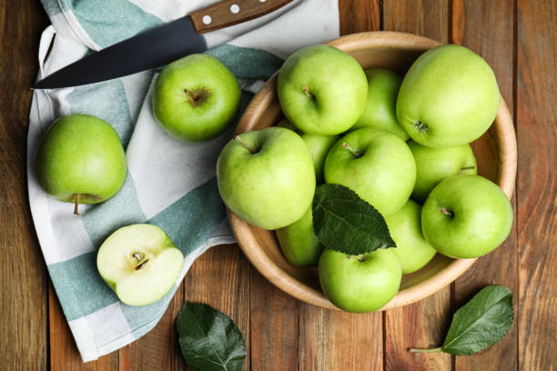 pommes vertes fraîches mûres et couteau sur table en bois, pose à plat - granny smith apple photos photos et images de collection