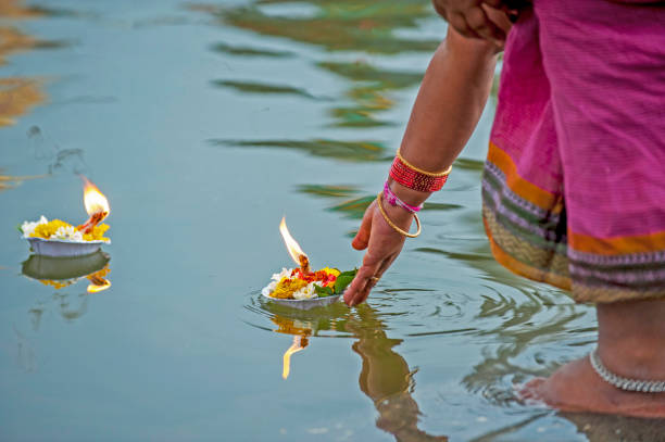 Indian woman puts candle on plate in water to pray the good luck in the puja ritual, India stock photo