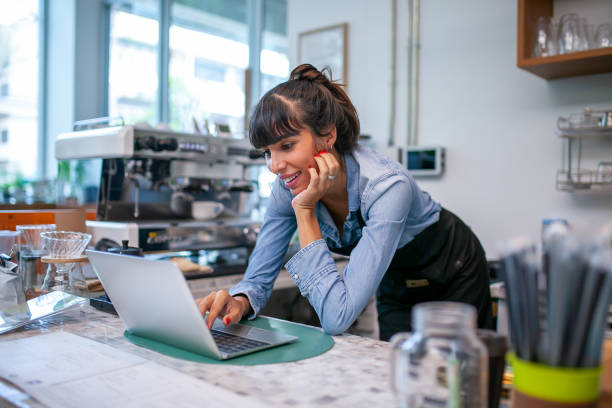 feliz mujer barista usando computadora portátil para tomar el pedido del cliente. - restaurant wireless technology office worker business fotografías e imágenes de stock