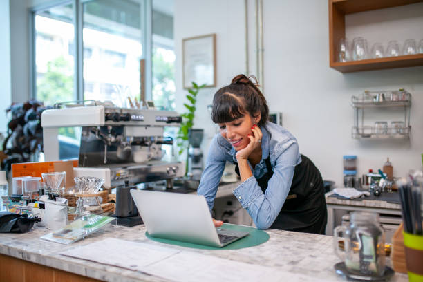 istock happy woman barista using laptop for take order from customer. 1387287896