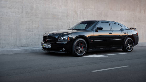 black Dodge Charger RT sedan in front of concrete wall Kyiv, Ukraine - April 28 2016: black Dodge Charger RT sedan in front of concrete wall. Three quarter view dodge charger stock pictures, royalty-free photos & images