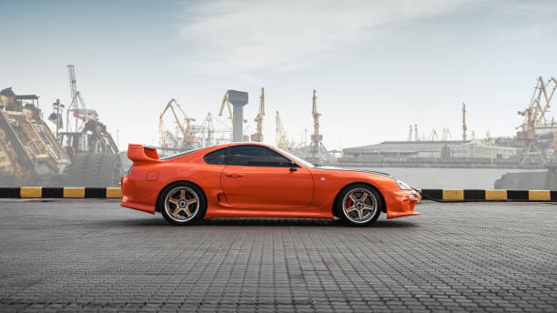 toyota supra naranja en puerto marítimo - street racing fotografías e imágenes de stock