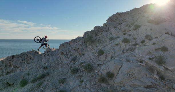 Aerial view of mountain biker on sunny coastal cliffs He carries the bike up the cliff, over the Pacific Ocean top view on people walking and cyclists riding stock pictures, royalty-free photos & images