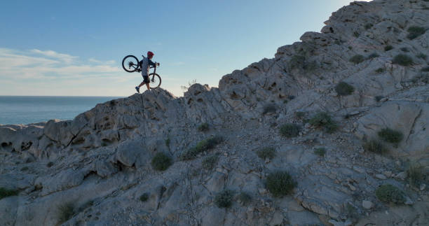 istock Aerial view of mountain biker on sunny coastal cliffs 1387288664