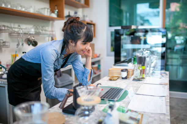 istock happy woman barista using laptop for take order from customer. 1387288675