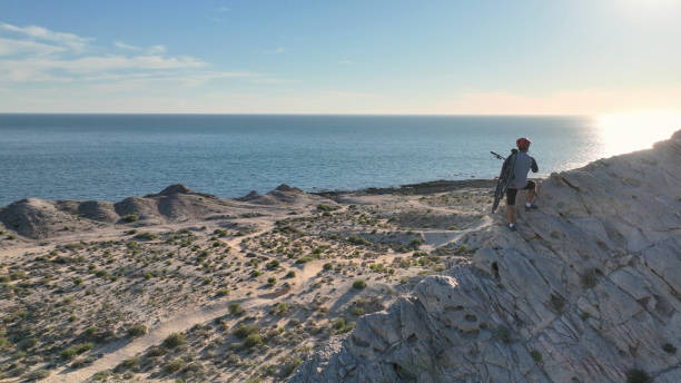 Aerial view of mountain biker on sunny coastal cliffs He carries the bike up the cliff, over the Pacific Ocean top view on people walking and cyclists riding stock pictures, royalty-free photos & images