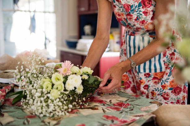Woman hand's making a wedding DIY bouquet. Close-up on hands, no face. Horizontal indoors shot.