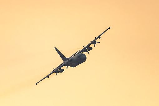 Lockheed C-130 Hercules of the Royal Dutch Air Force flying in mid air during sunset near Deelen airflield at the Veluwezoom nature reserve in Gelderland, The Netherlands.