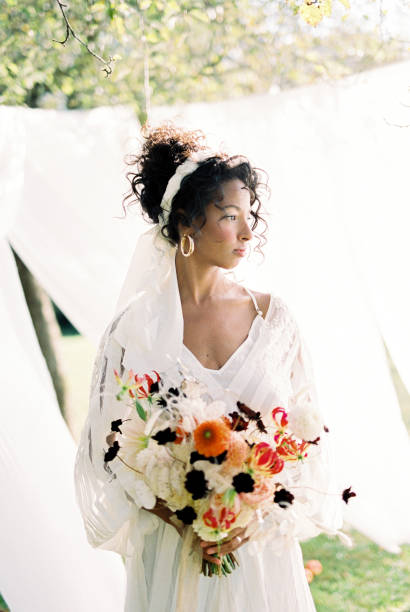 istock Bride Holding Bouquet Standing Outdoors 1387290775