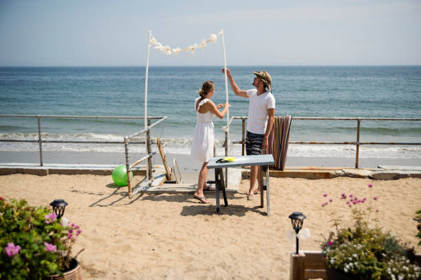 Couple putting on DIY wedding decorations by the beach.