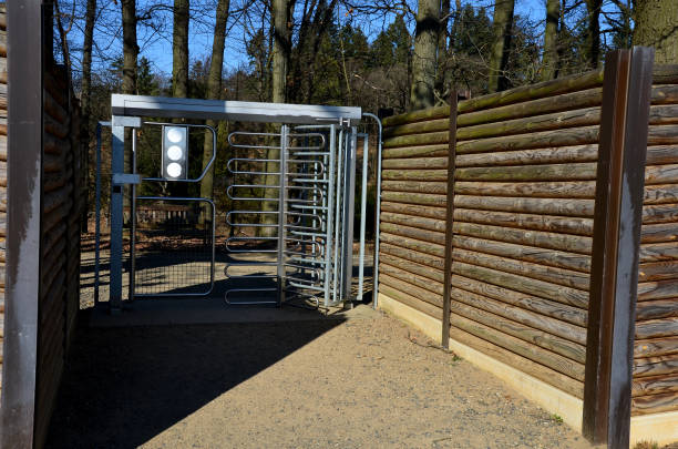 tourniquet vers le champ protégeant contre l’entrée d’autres animaux. les visiteurs entrent par une porte barrée en acier inoxydable. clôture, protection contre le bruit. les poteaux de la palissade sont enfermés dans des poutres d’acier - formal garden wall ornamental garden walled garden photos et images de collection