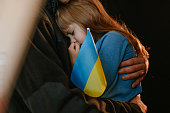 Portrait of rescued little girl with her father holding Ukrainian flag